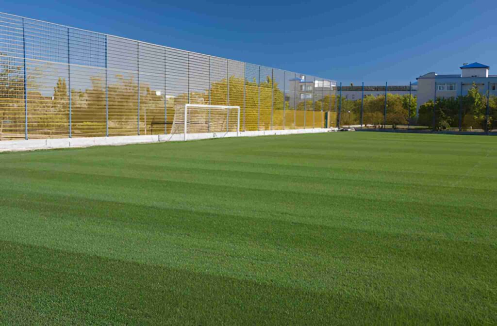 Football turf ground with green artificial grass and boundary fencing